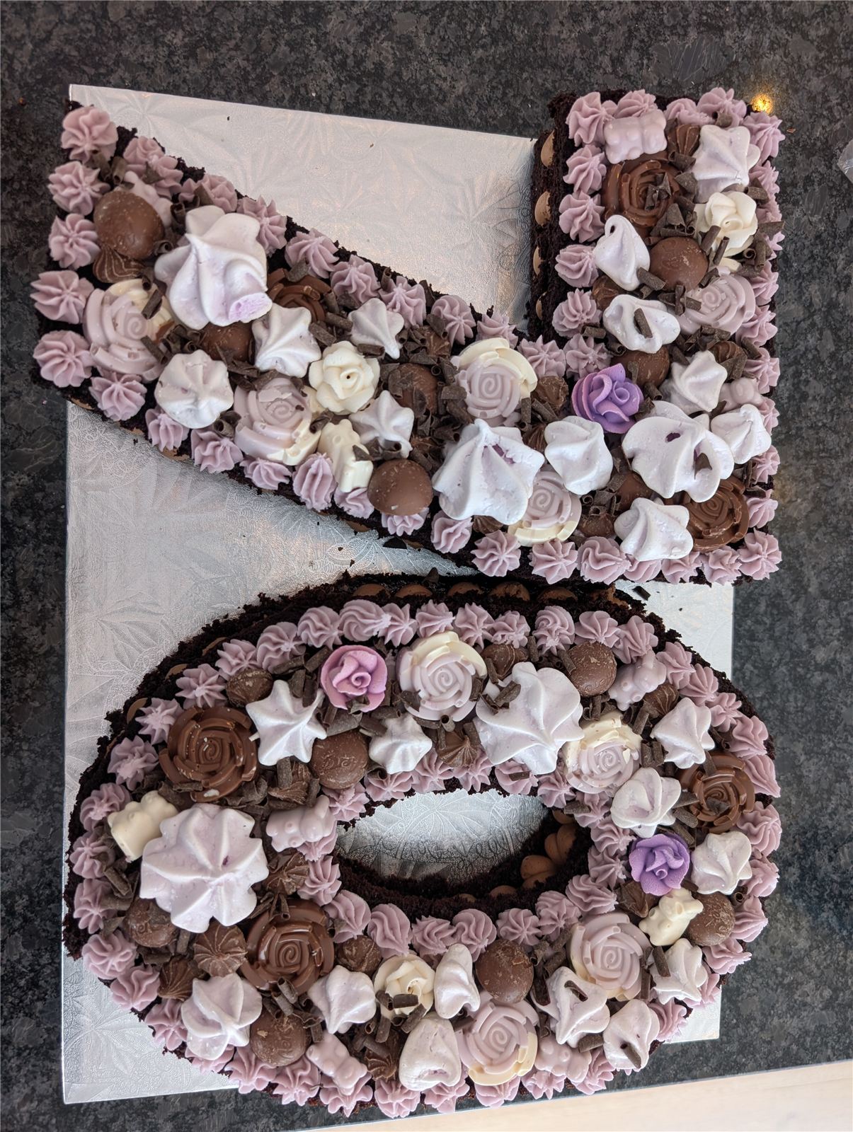 Chocolate number-shaped cake decorated with roses and meringues