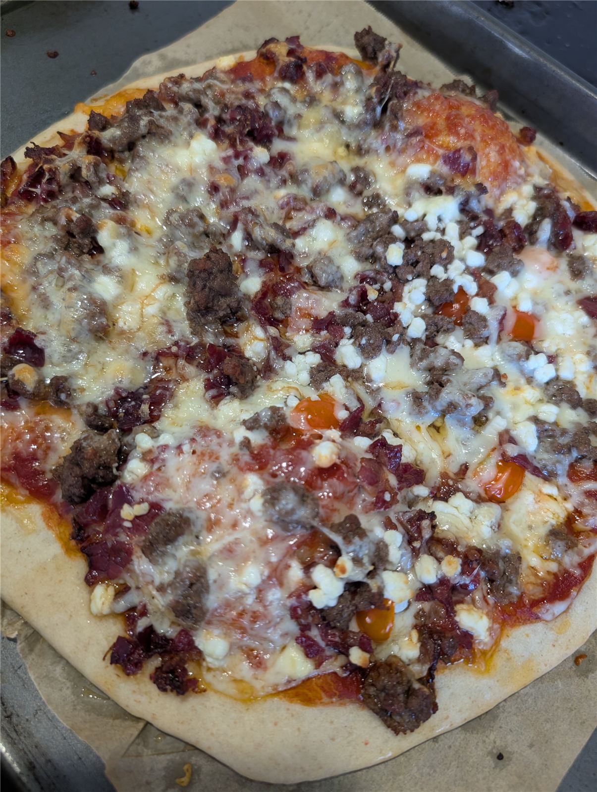 Homemade pizza topped with beef, bacon, and feta