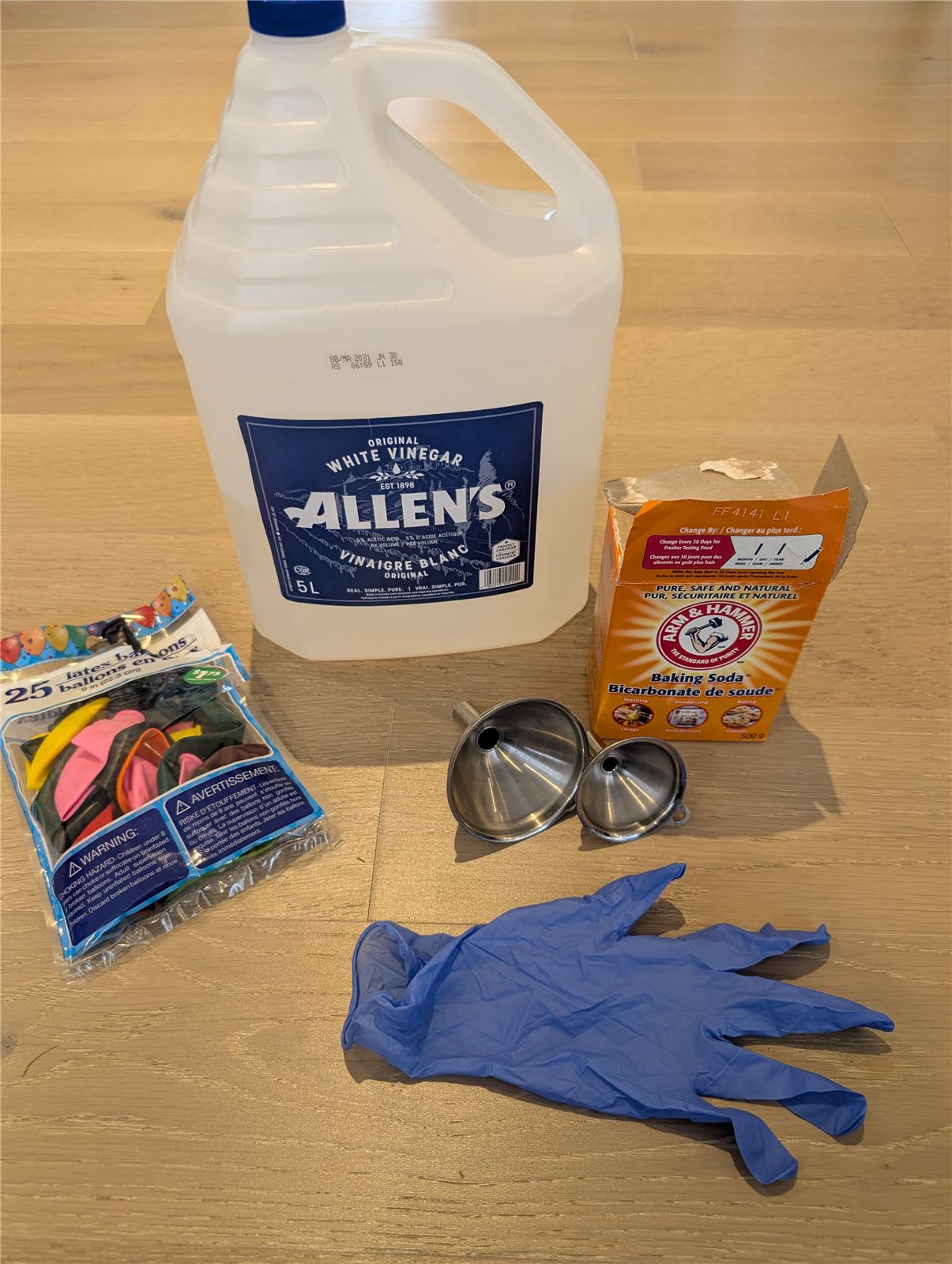 Materials for the balloon bomb experiment: vinegar, baking soda, balloons, funnel, and gloves