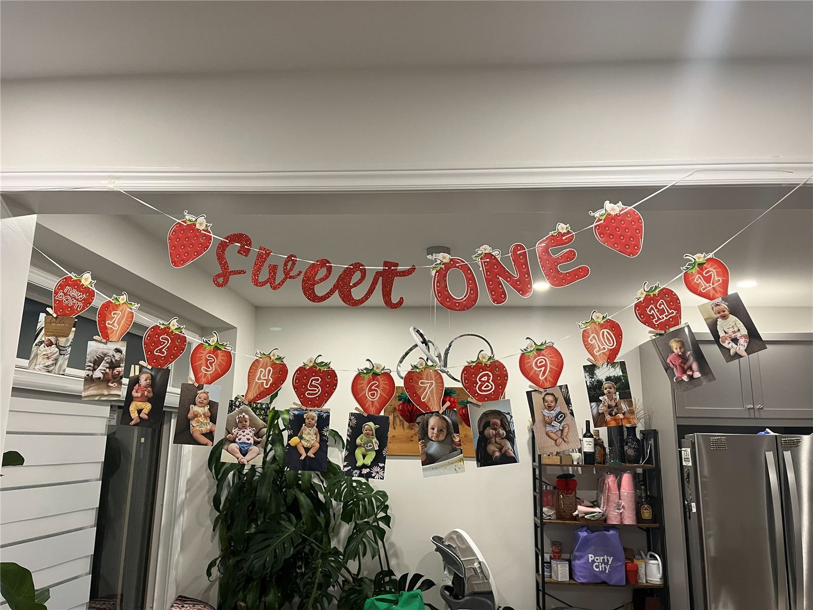 Sweet ONE garland with twelve monthly baby photos clipped under numbered strawberries