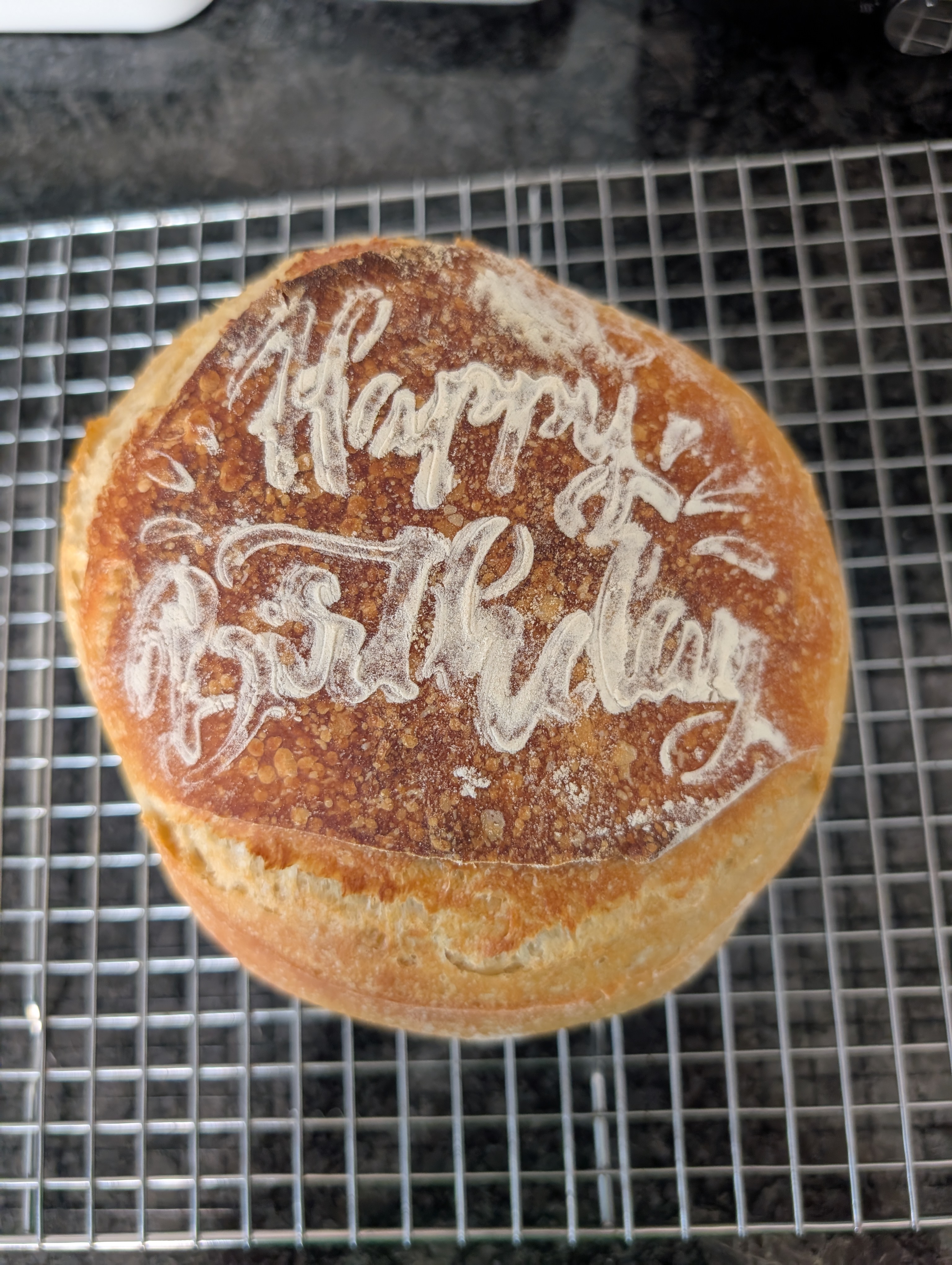 Whole sourdough loaf with Happy Birthday scored and dusted in flour on top