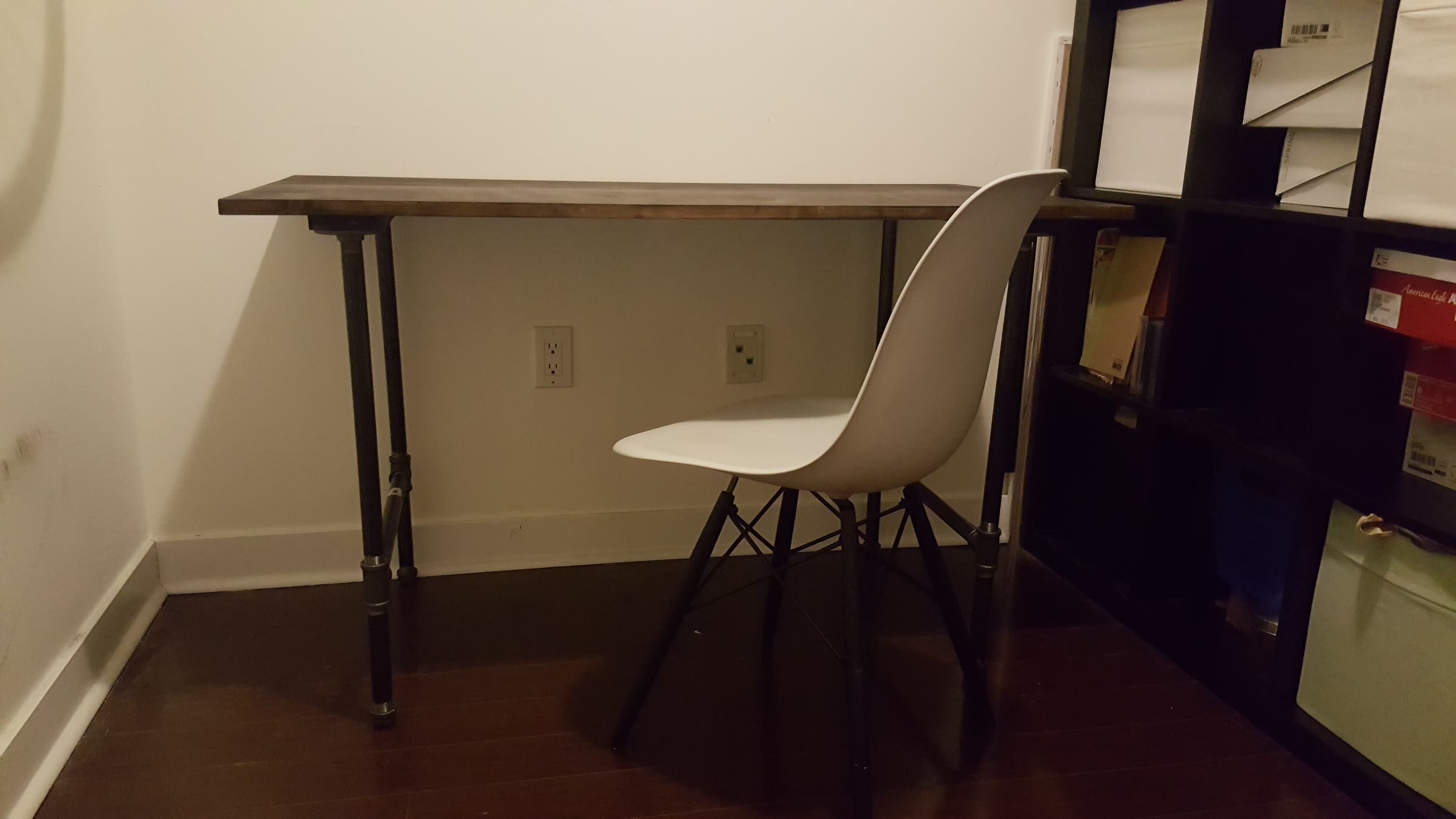 Front view of the finished DIY desk against a wall with a white chair pulled up
