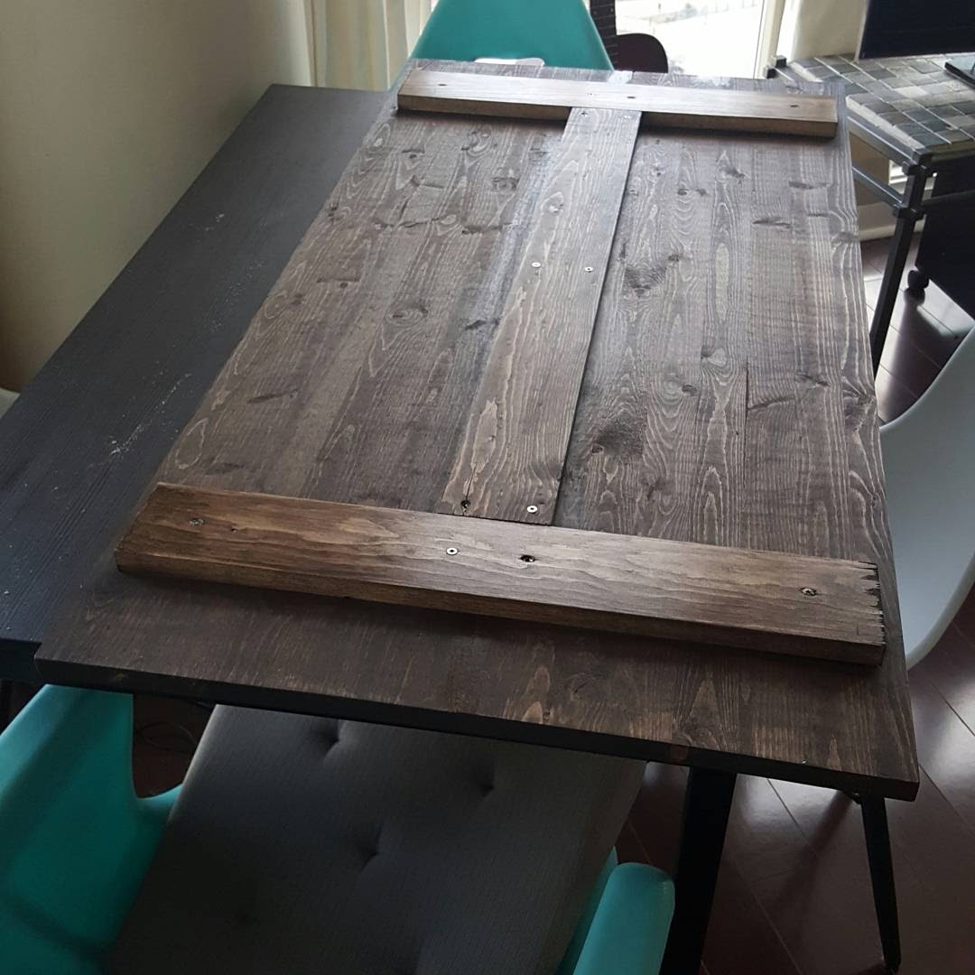 Stained tabletop turned upside down with two short 1x4 support boards across the ends and one long board down the middle, screwed in