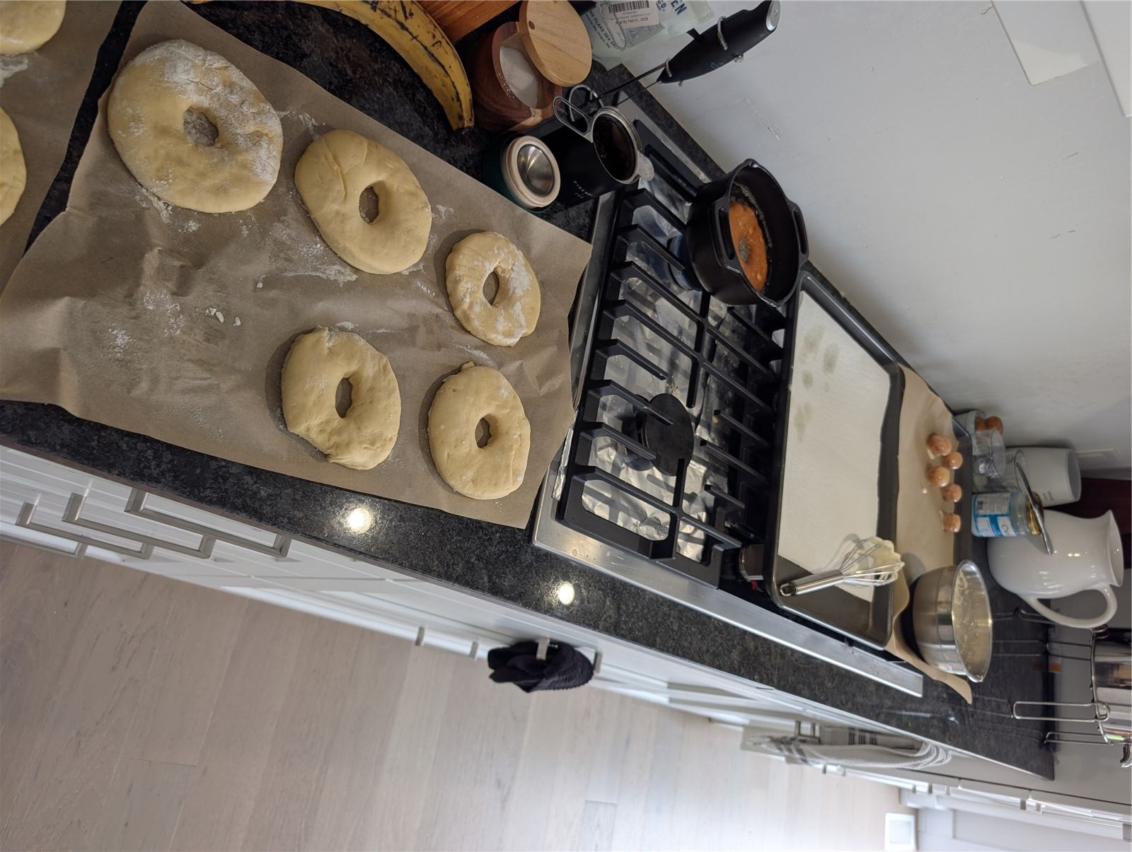 Cut donut dough rings proofing on parchment paper next to the stove