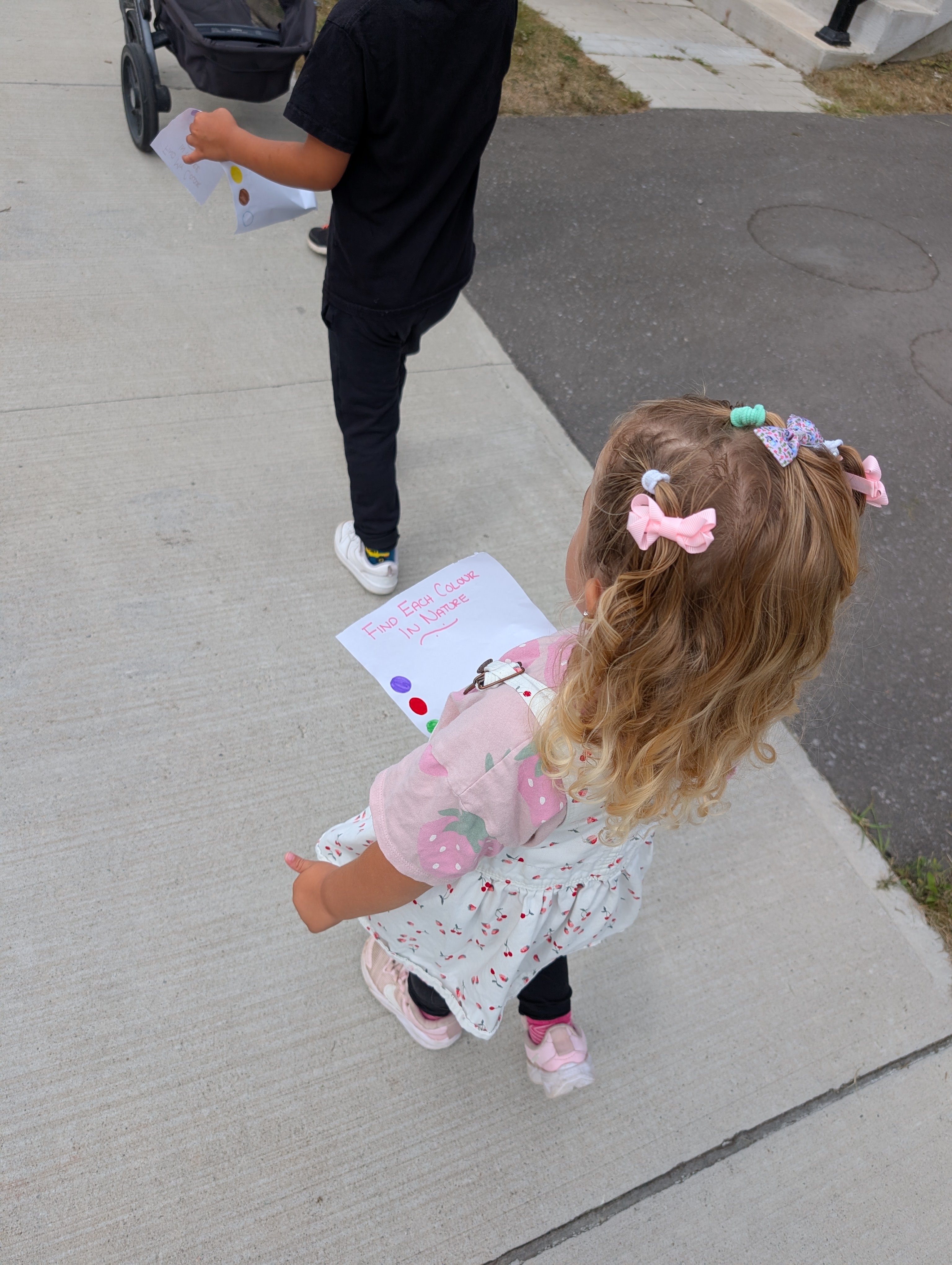 Kids walking outside holding their find-each-colour-in-nature checklists