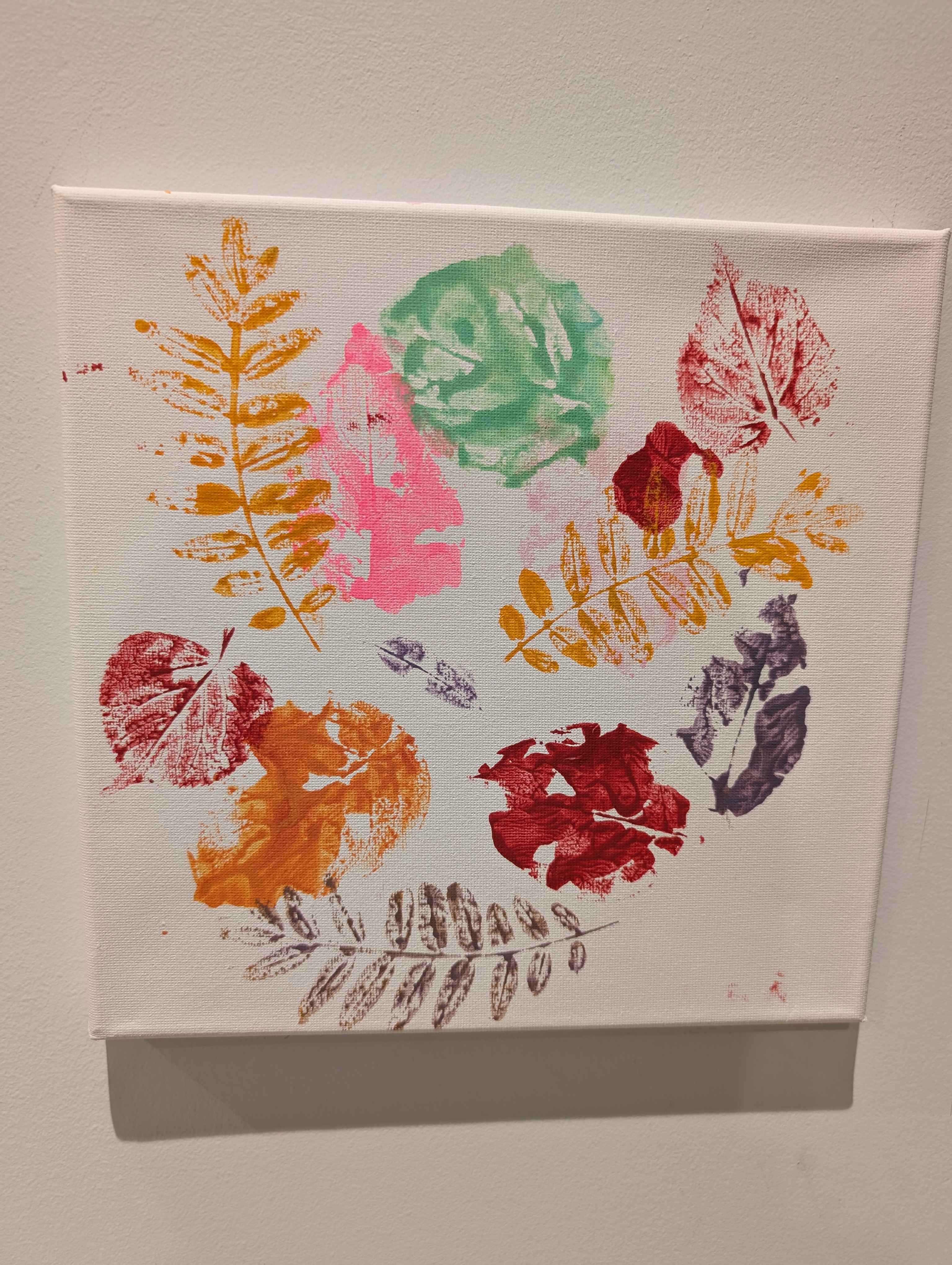 Canvas covered in colorful leaf-print paintings in pink, green, orange, and purple