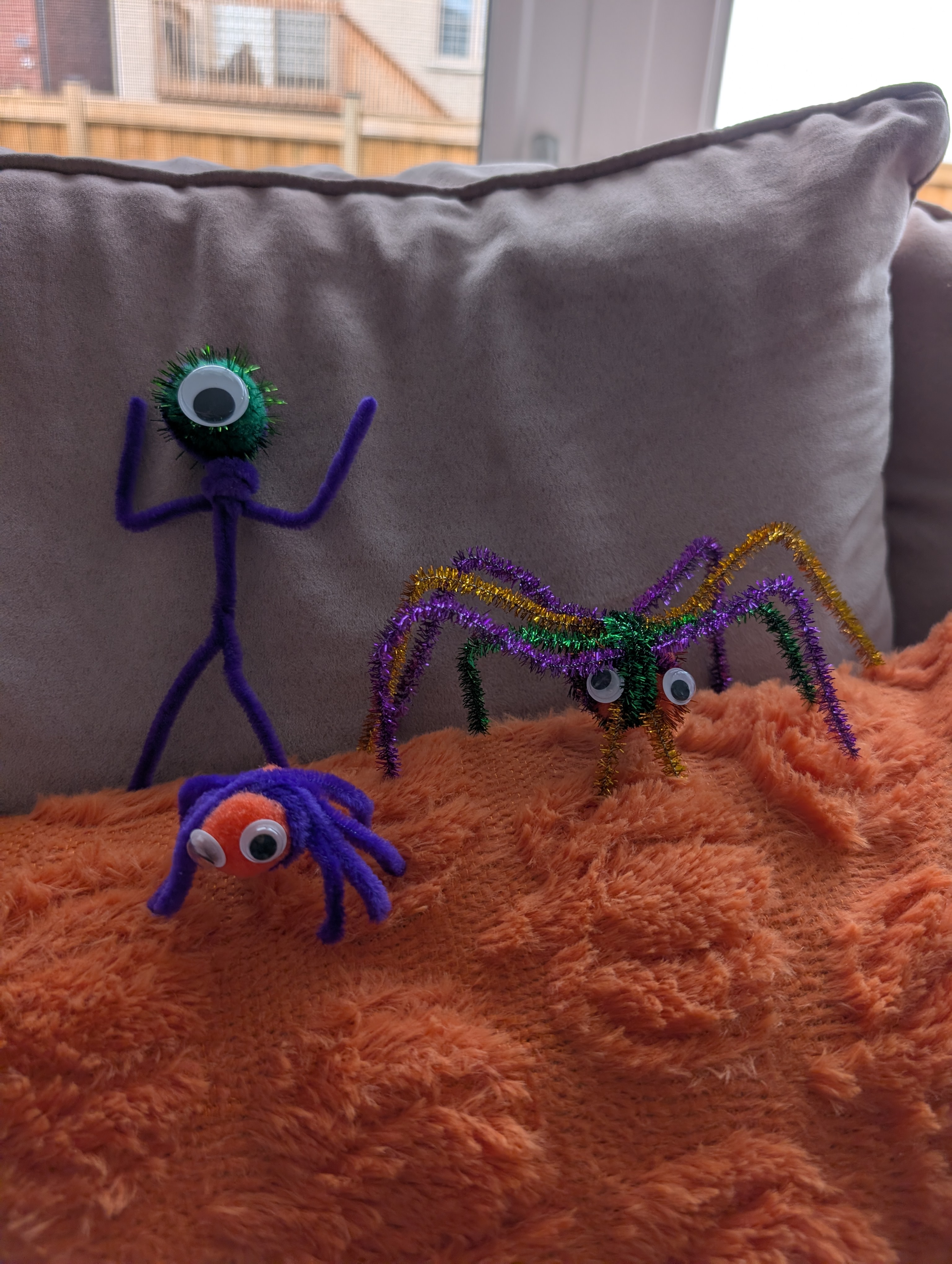 Pipe cleaner spiders and a one-eyed pipe cleaner cyclops character lined up together