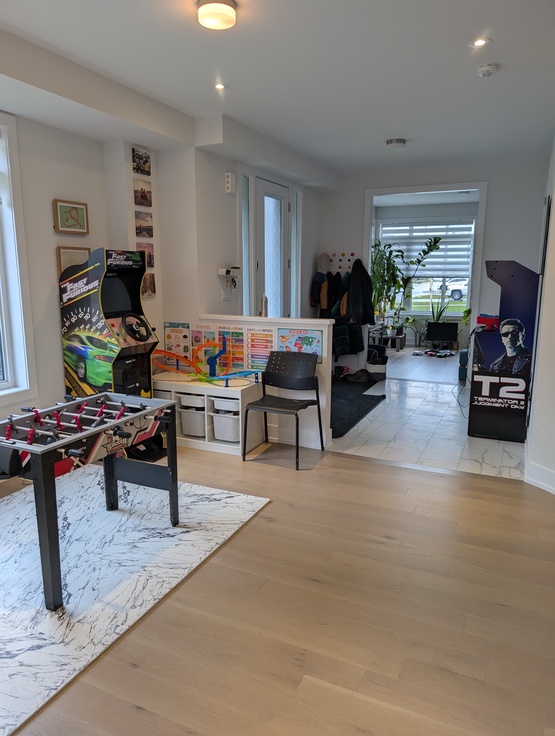Rented arcade machines set up in a living room: a Fast and Furious cabinet, a foosball table, and a Terminator 2 Judgment Day cabinet
