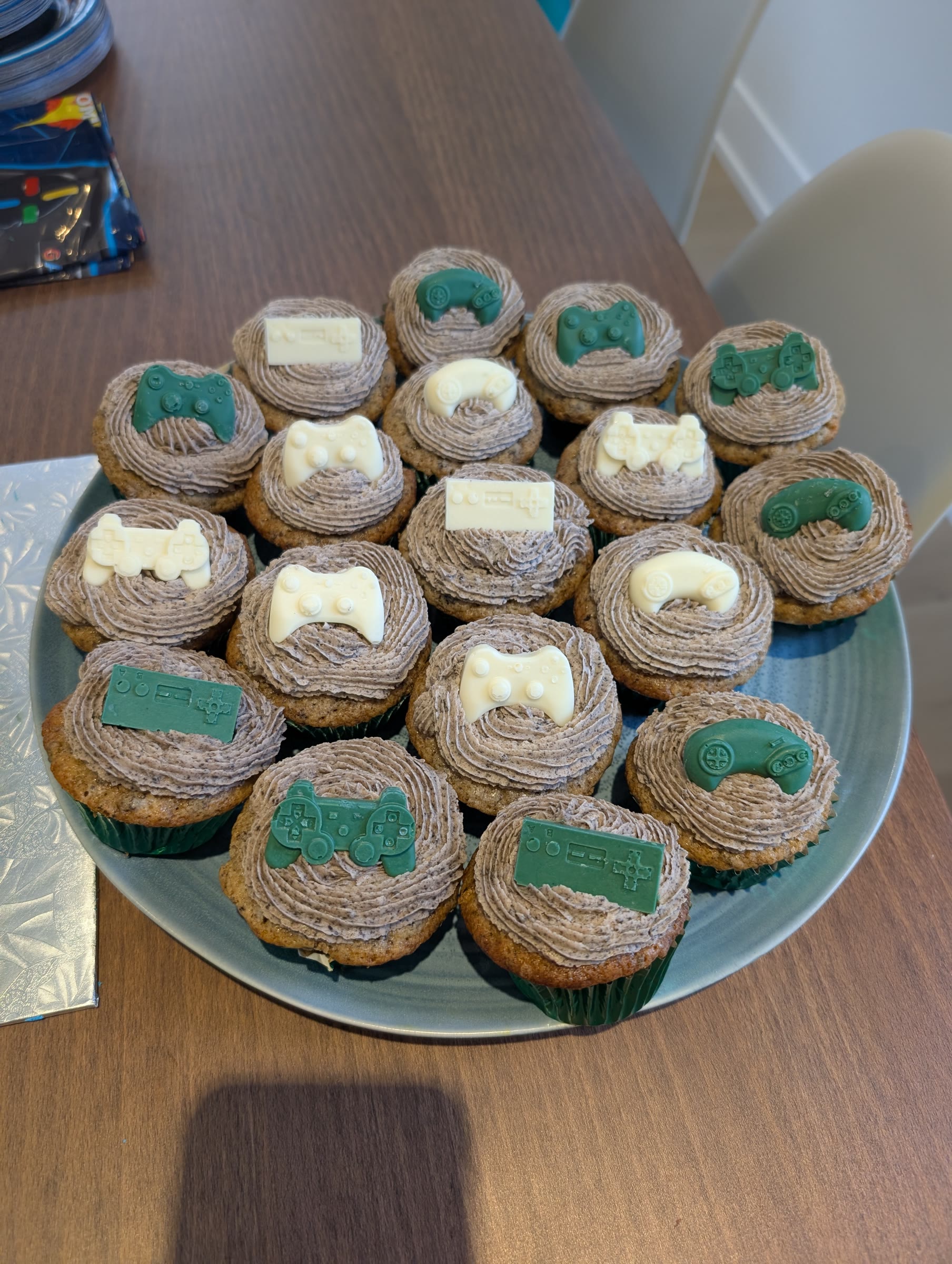 Plate of cookies and cream cupcakes with swirls of Oreo buttercream, each topped with a green or white chocolate video game controller