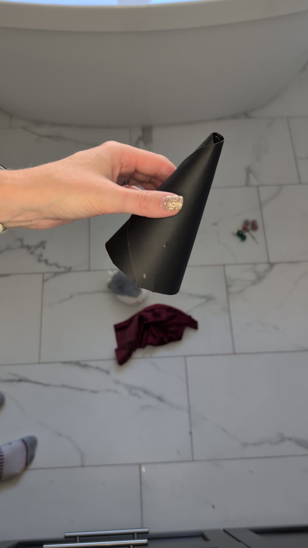 A black craft paper cone held in one hand with a piece of red velvet on the floor below