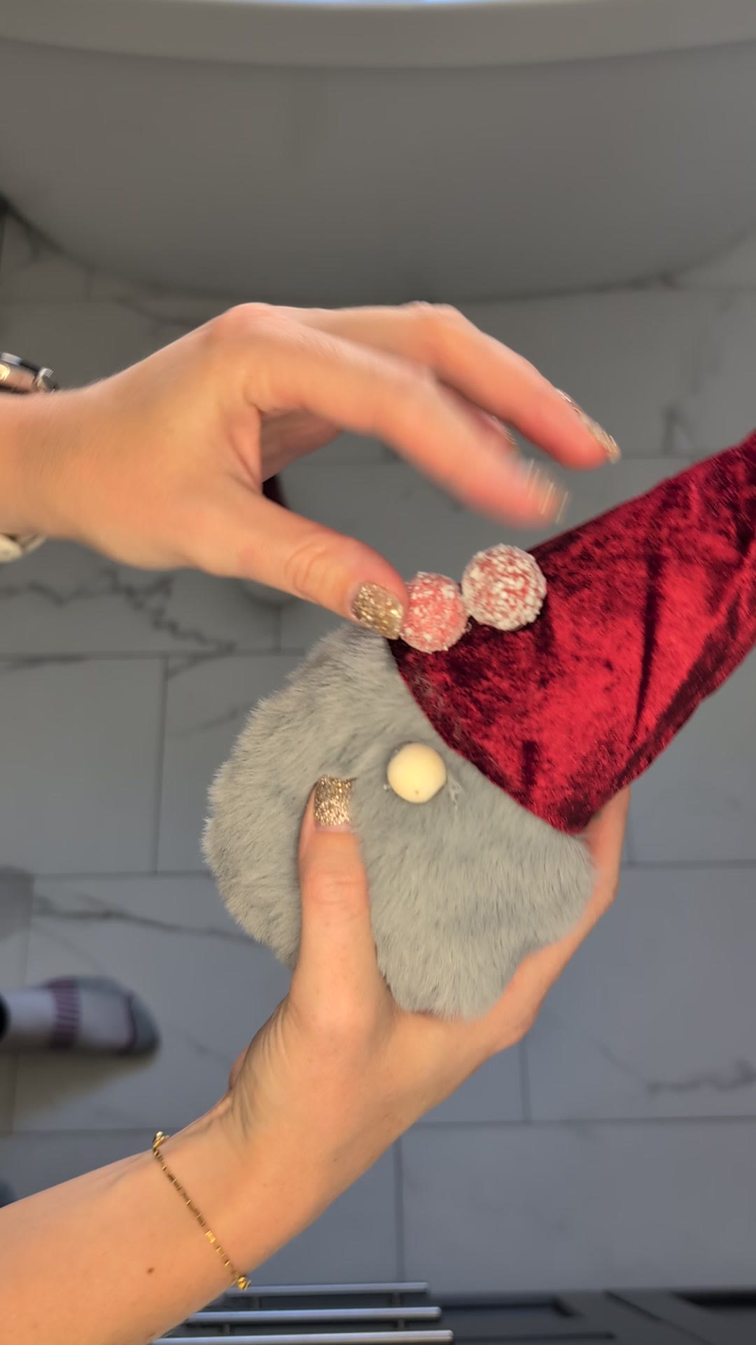 Two finished gnomes held up in the air, with berries on the red hats and bells on top