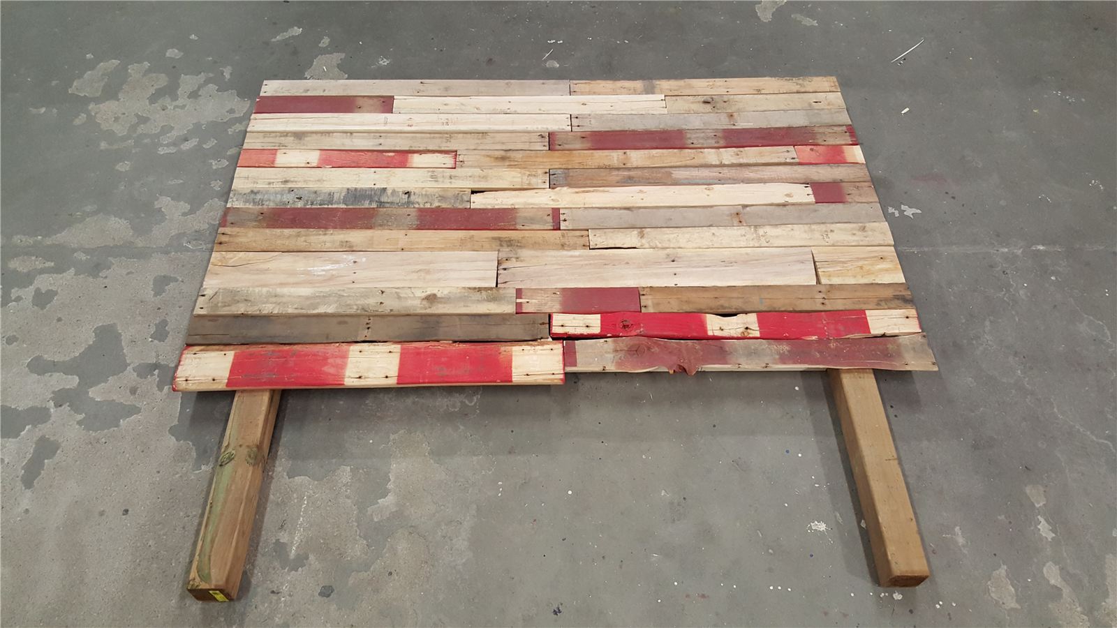 Assembled headboard laid flat on the garage floor with cedar 4x4 legs attached