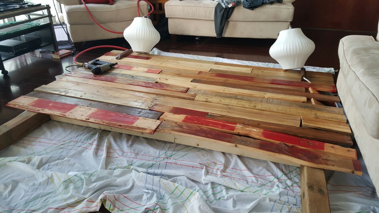 Headboard boards laid out on a drop cloth in the living room next to two pendant lamps