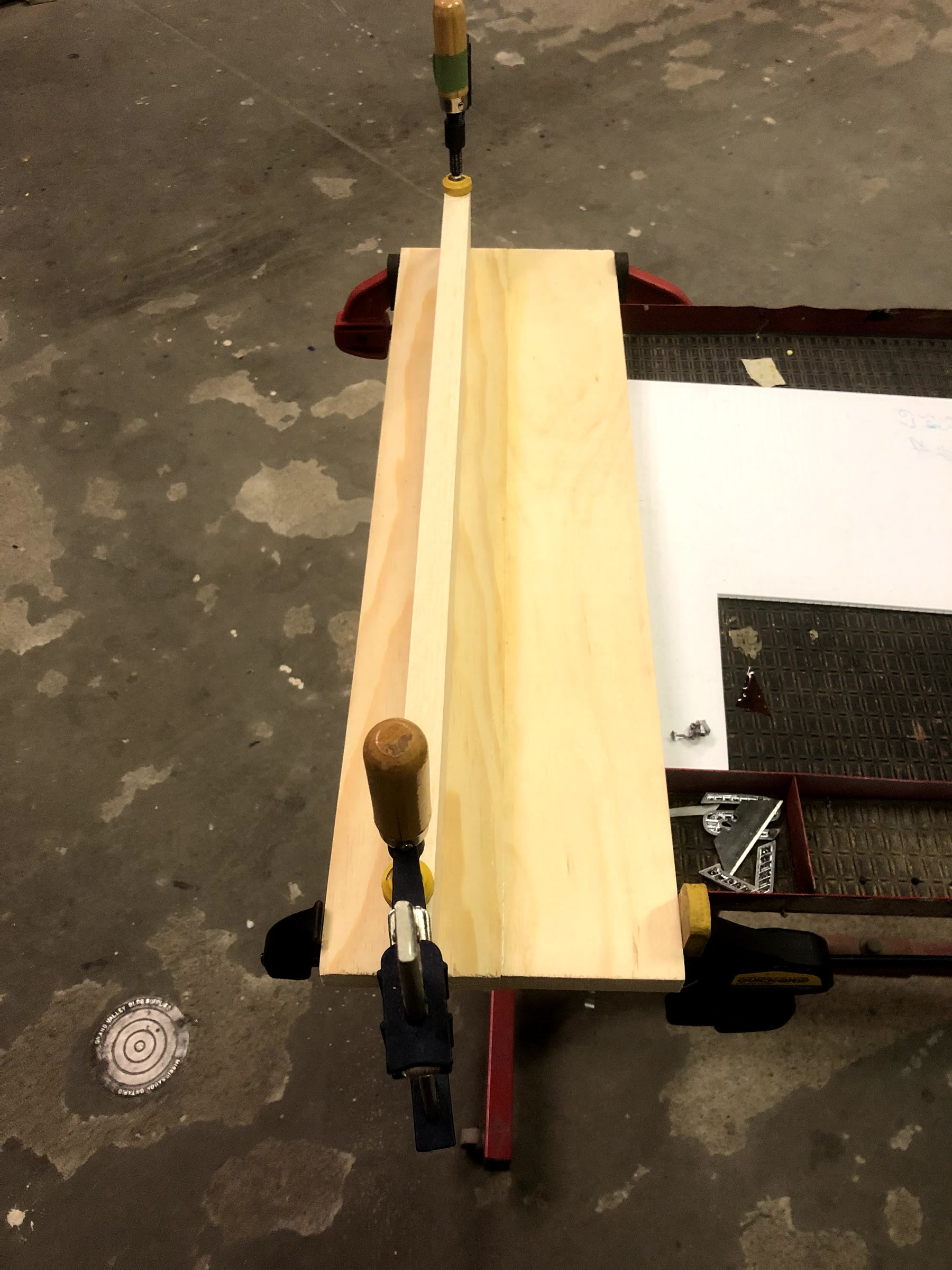 Top view of the glued pine boards held with clamps: two boards side by side with a third board standing on edge as the ledge