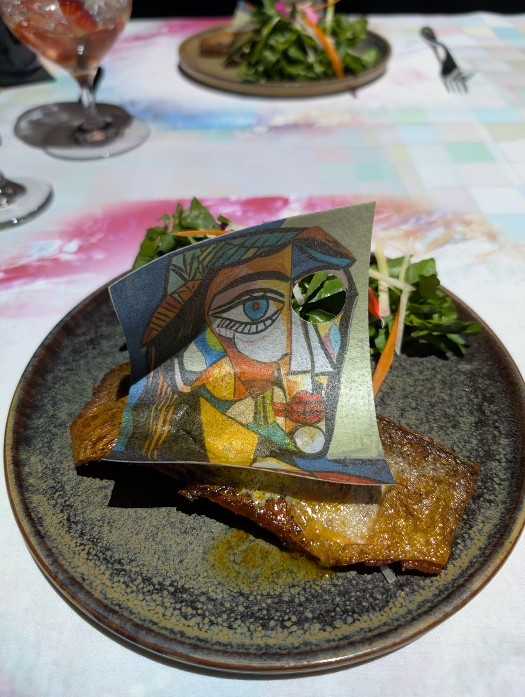 A plate of crispy-skinned fish topped with an edible cubist-style portrait print, from the immersive art dinner