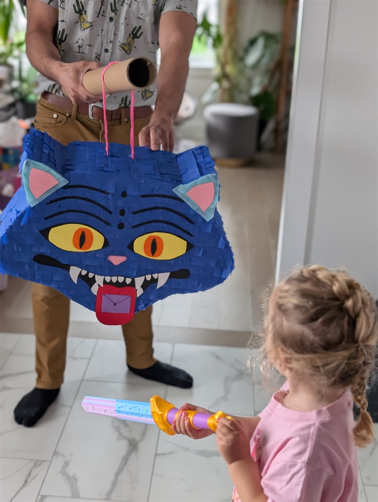 Dad holding up the finished pinata while a child holds a toy sword