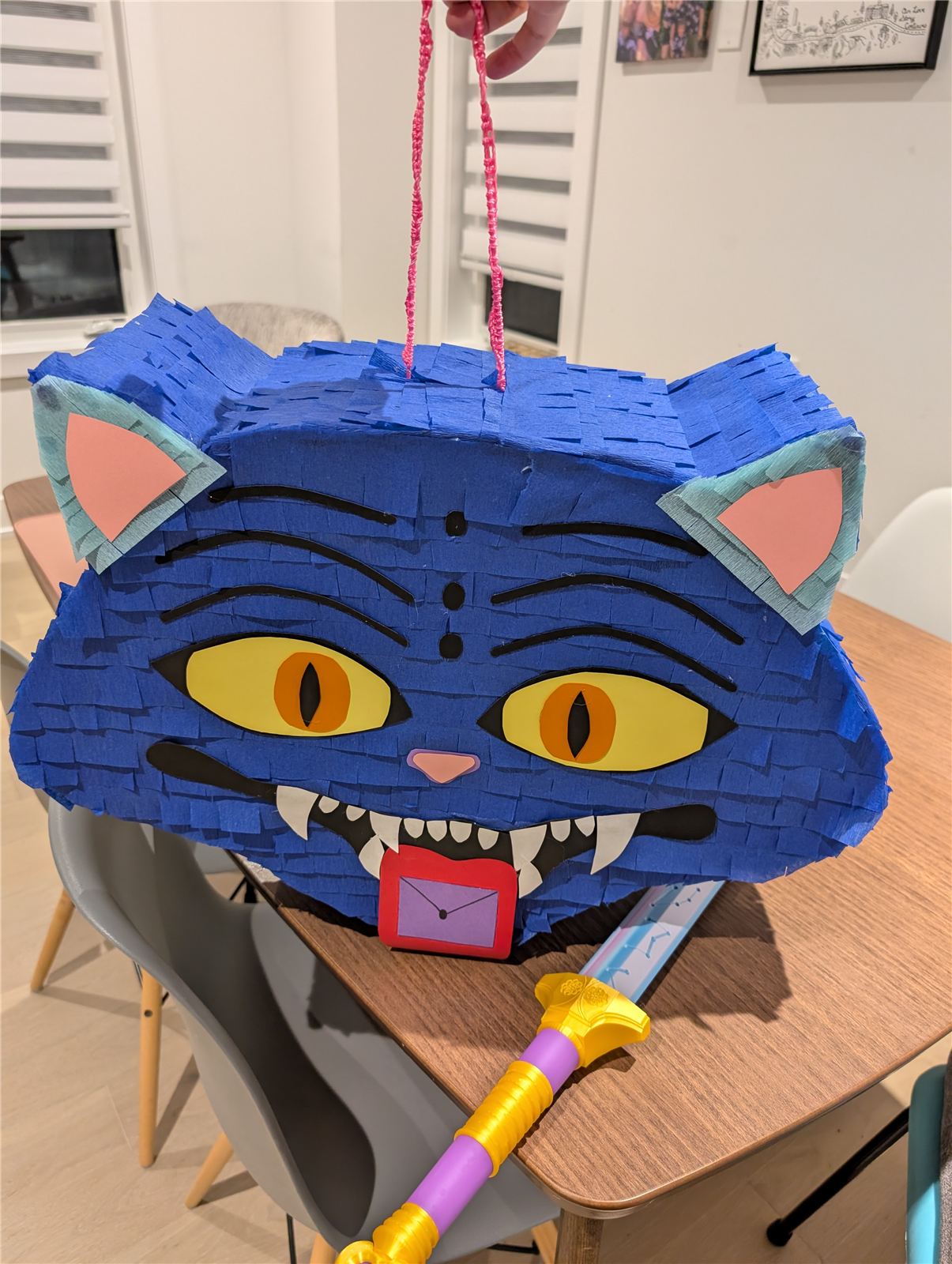 Finished blue crepe paper pinata with a demon cat face, ready to be hung