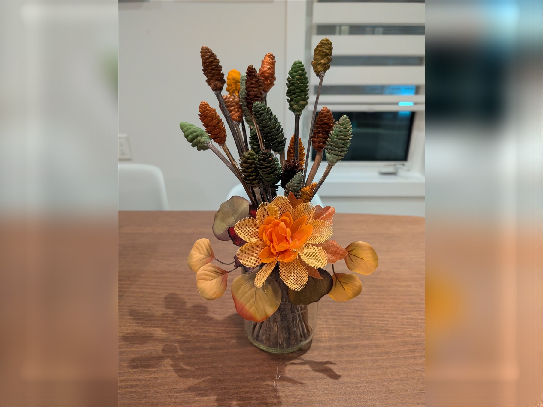 Bouquet of painted pinecones on sticks in a mason jar with a burlap flower