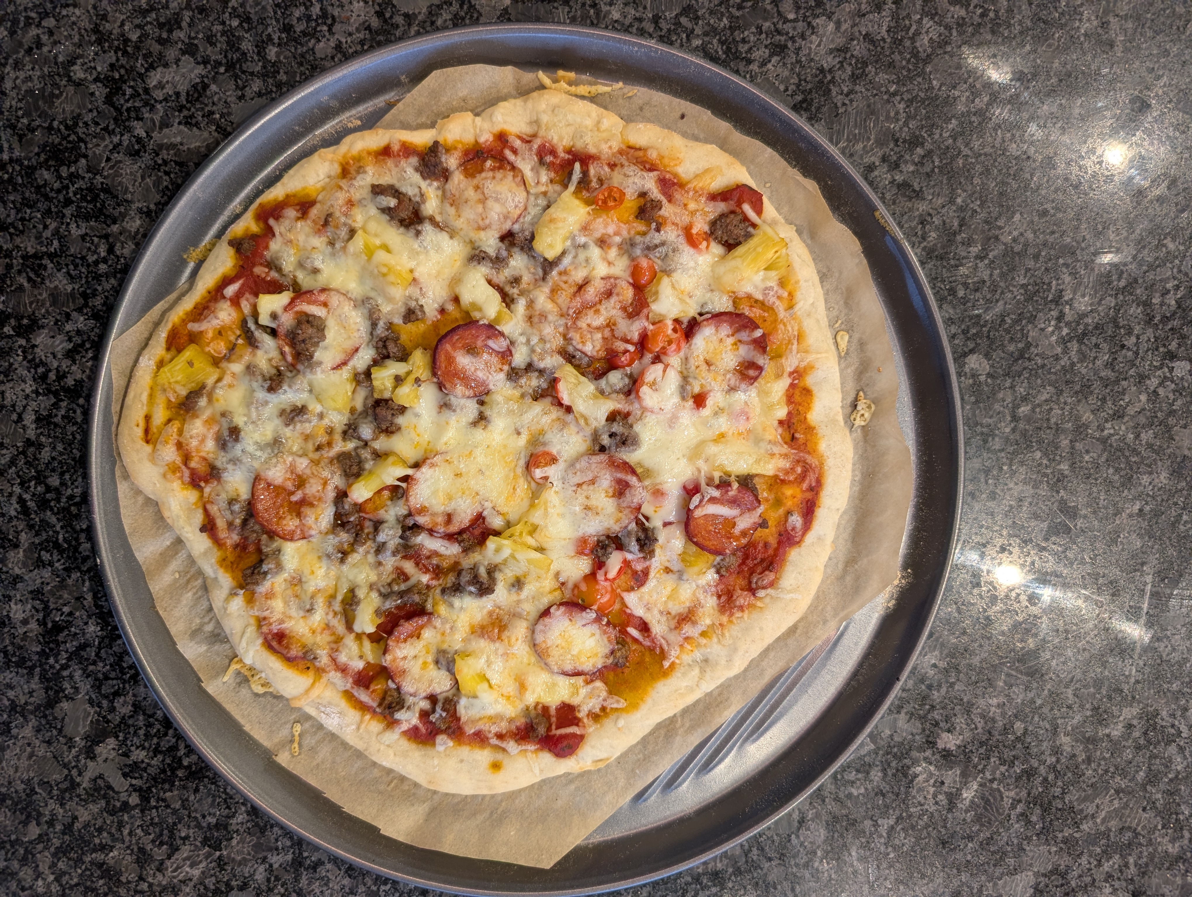 Finished sourdough discard pizza topped with pepperoni, sausage, banana peppers, and cheese