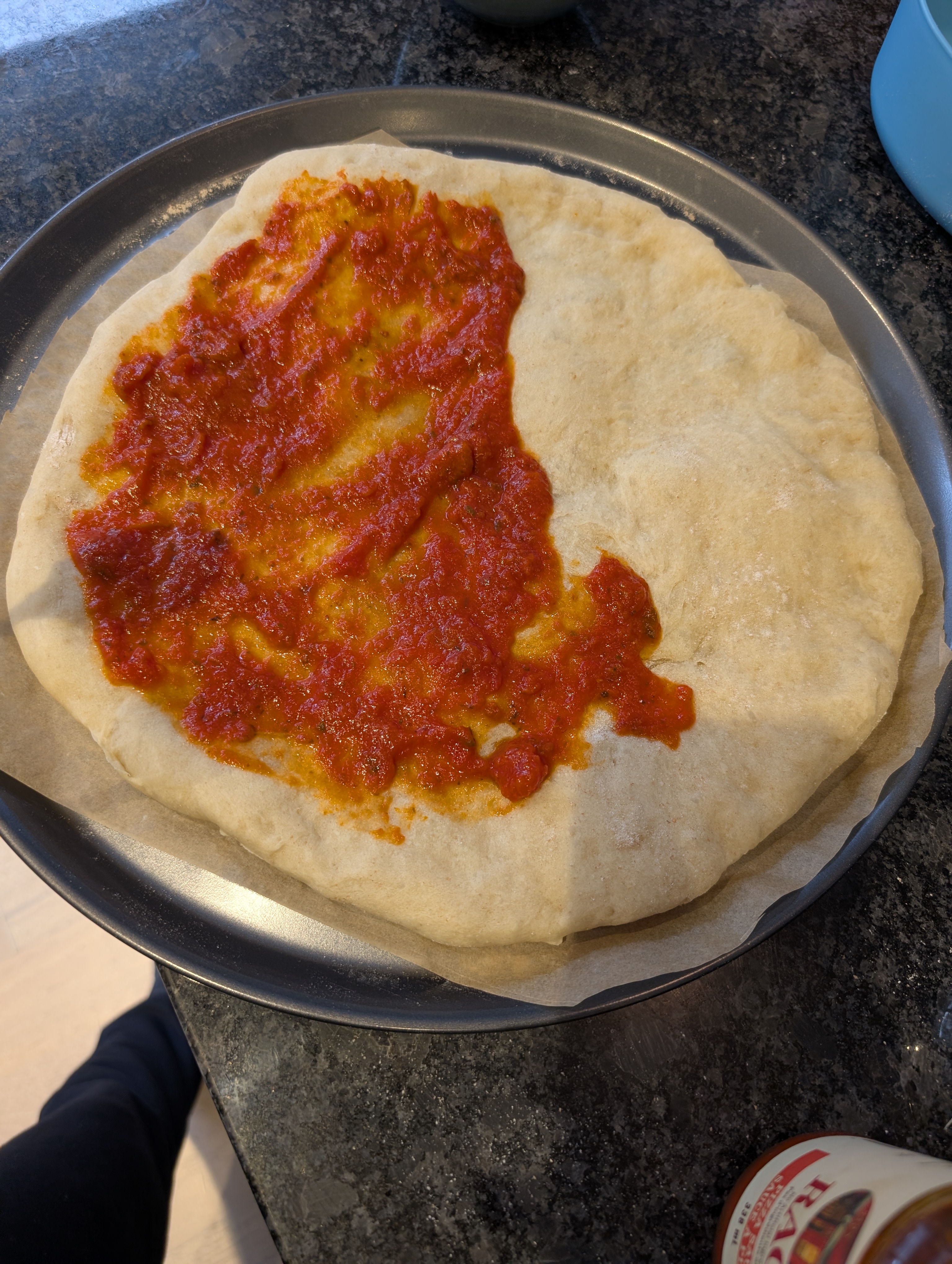 Stretched pizza dough spread with a thin layer of red sauce