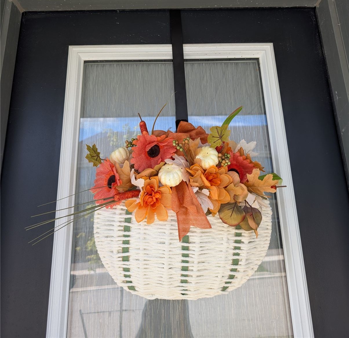 Finished cozy yarn pumpkin wreath hanging on a front door