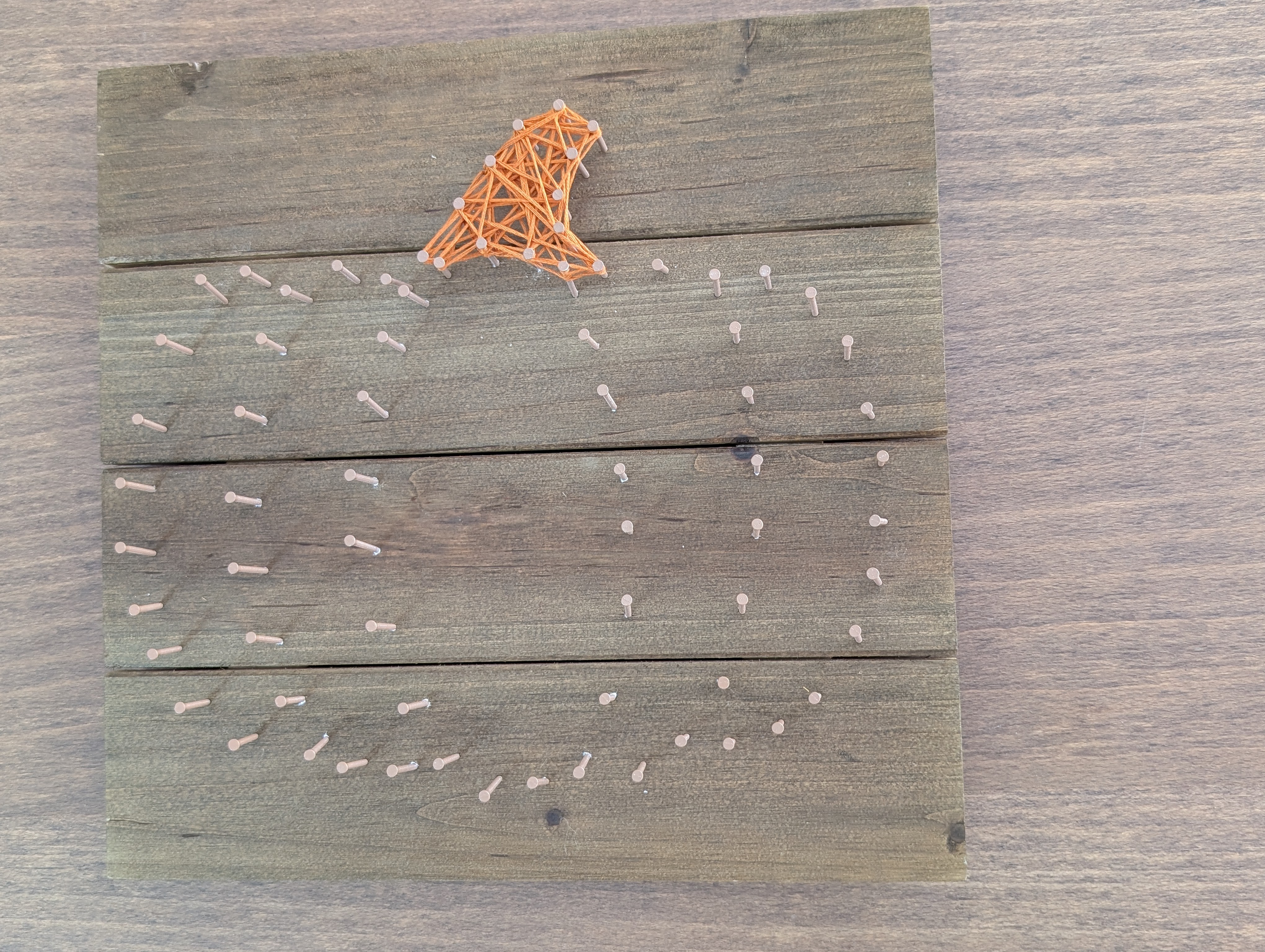 Stem of the pumpkin strung solid in orange embroidery floss while the body outline is still just nails