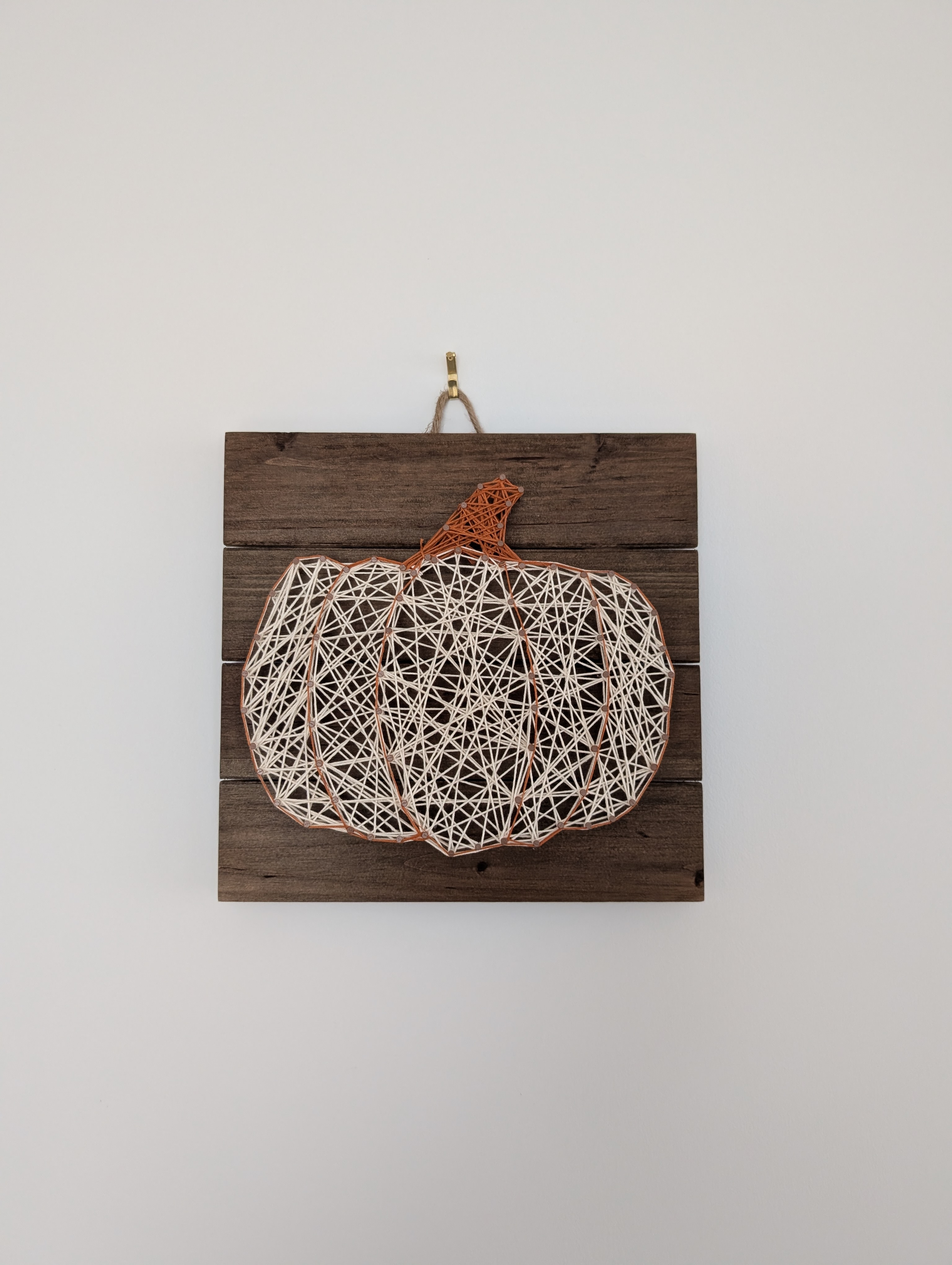 Finished pumpkin string art hanging on a wall