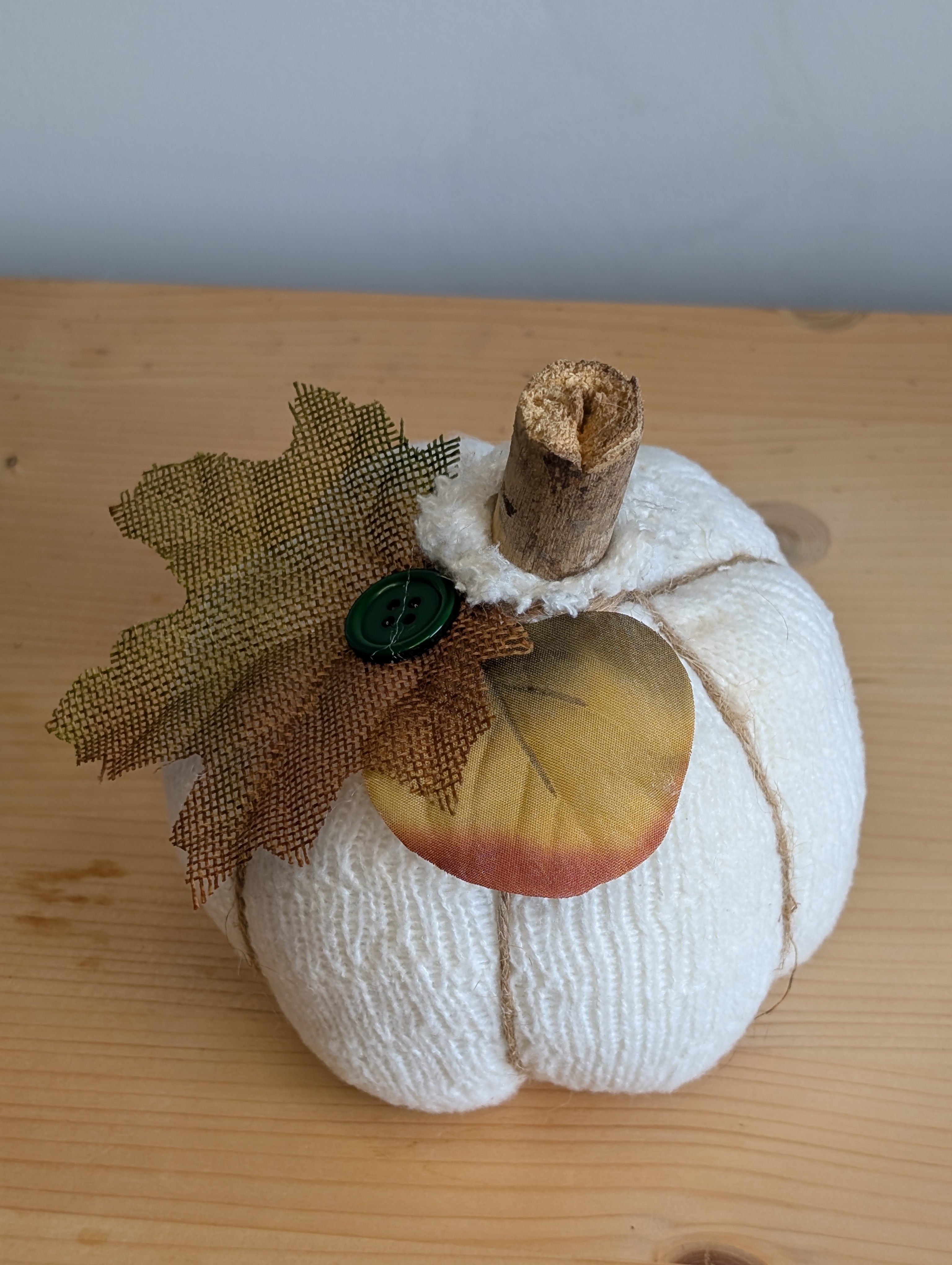 Finished cream sock pumpkin with a stick stem, twine ridges, and a burlap leaf
