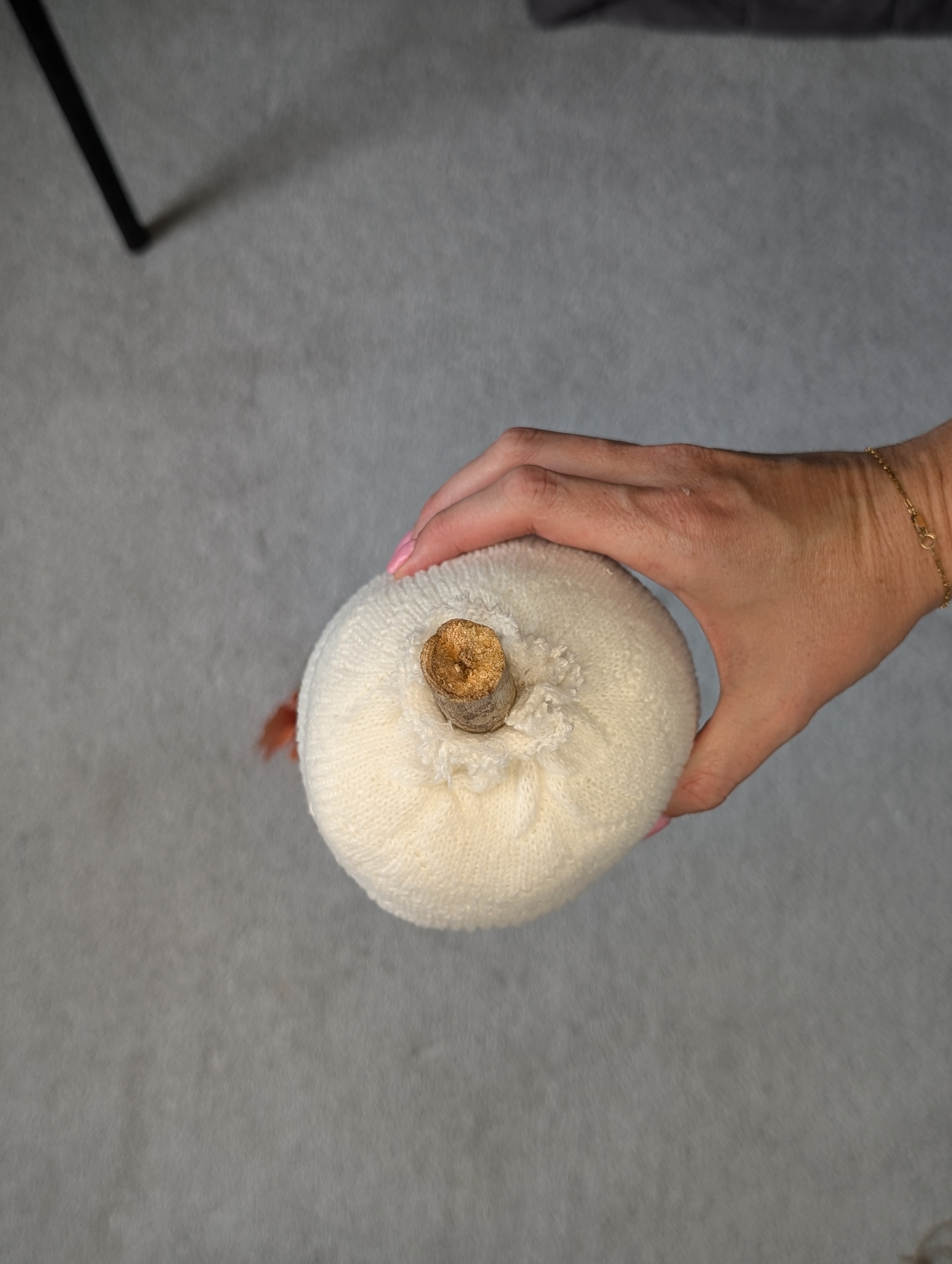 Top view of the sock pumpkin with the stick stem sticking out of the gathered sock