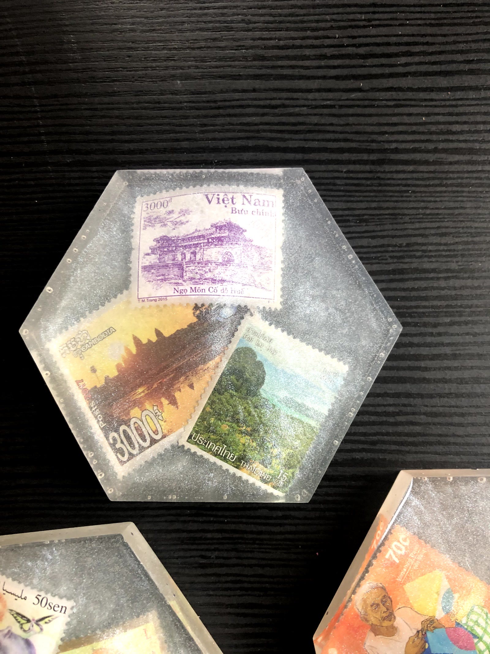 Close-up of a hexagon resin coaster with Vietnam, Cambodia and Thailand stamps set in grey glitter resin