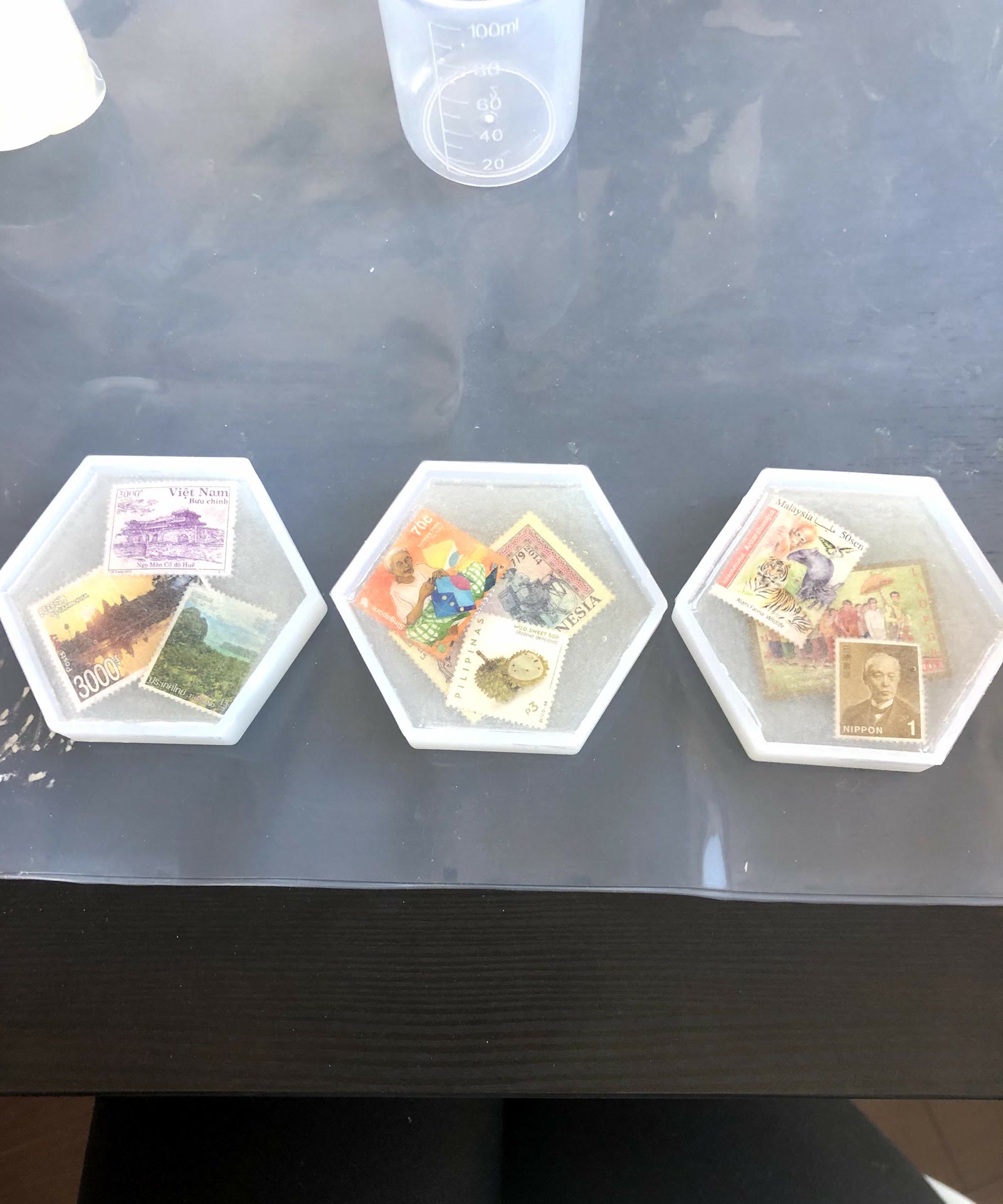 Three hexagon molds of stamps covered in glittery resin, curing on a table