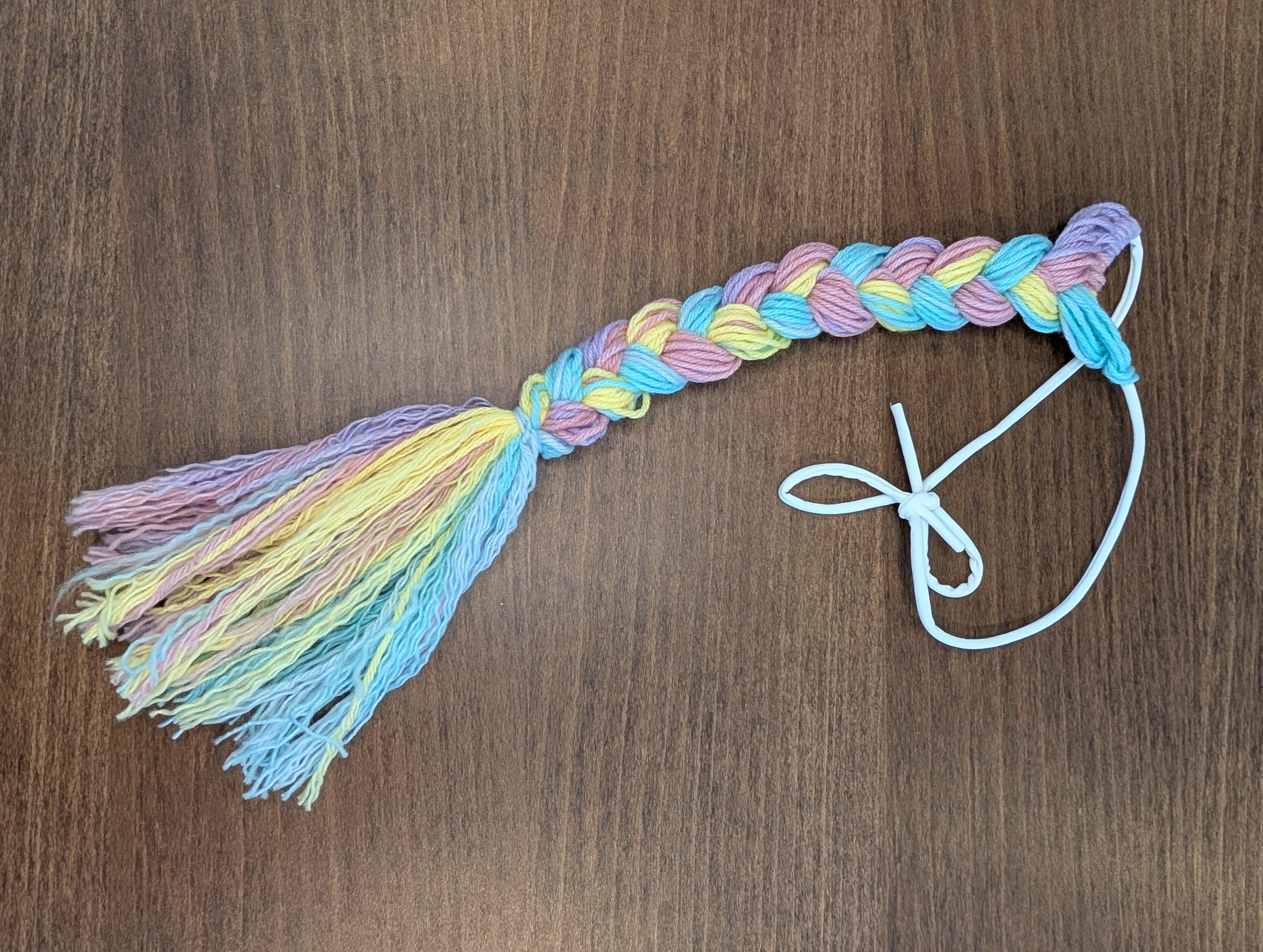 Finished rainbow yarn unicorn tail with a braided top and a fluffy fringed end