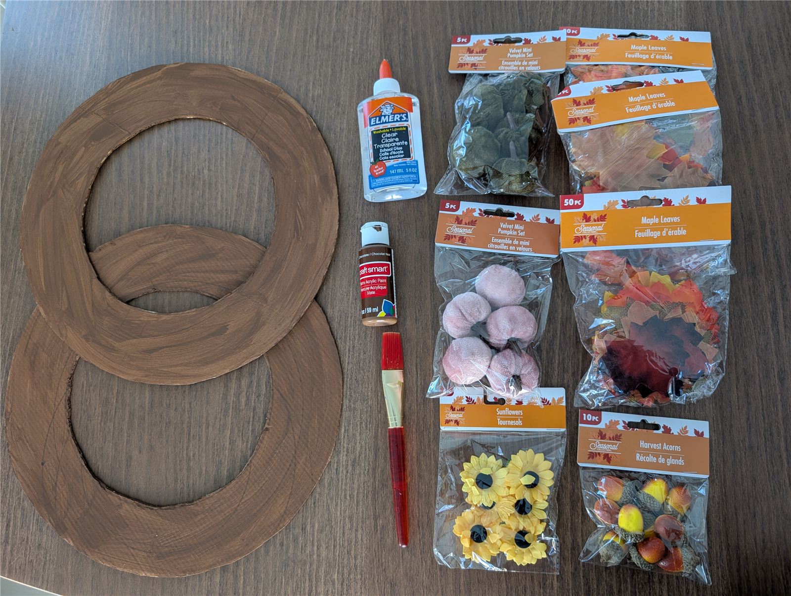 Materials laid out: cardboard rings, brown paint, glue, and Dollar Tree fall leaves and pumpkins