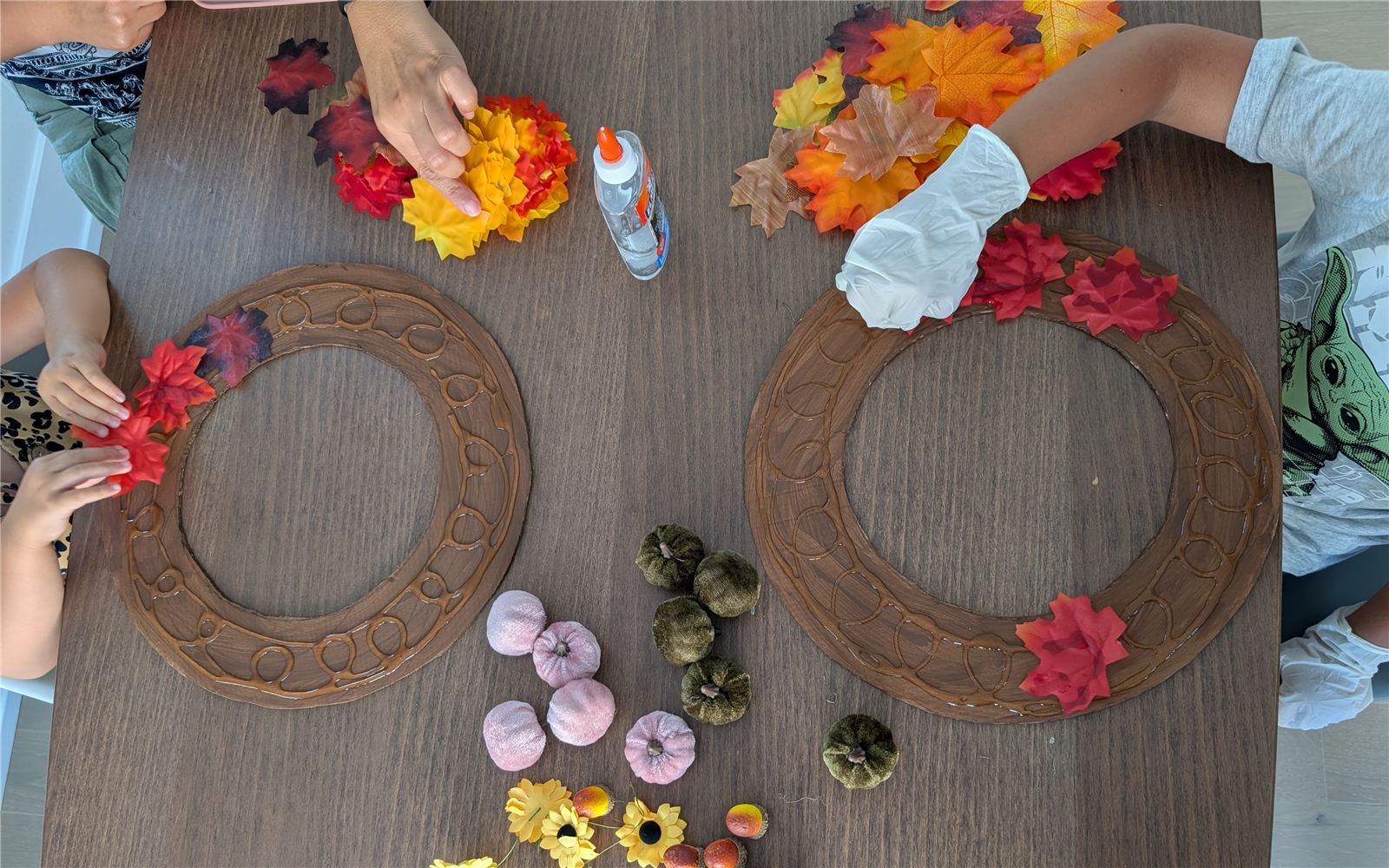 Kids gluing maple leaves onto the wreath rings